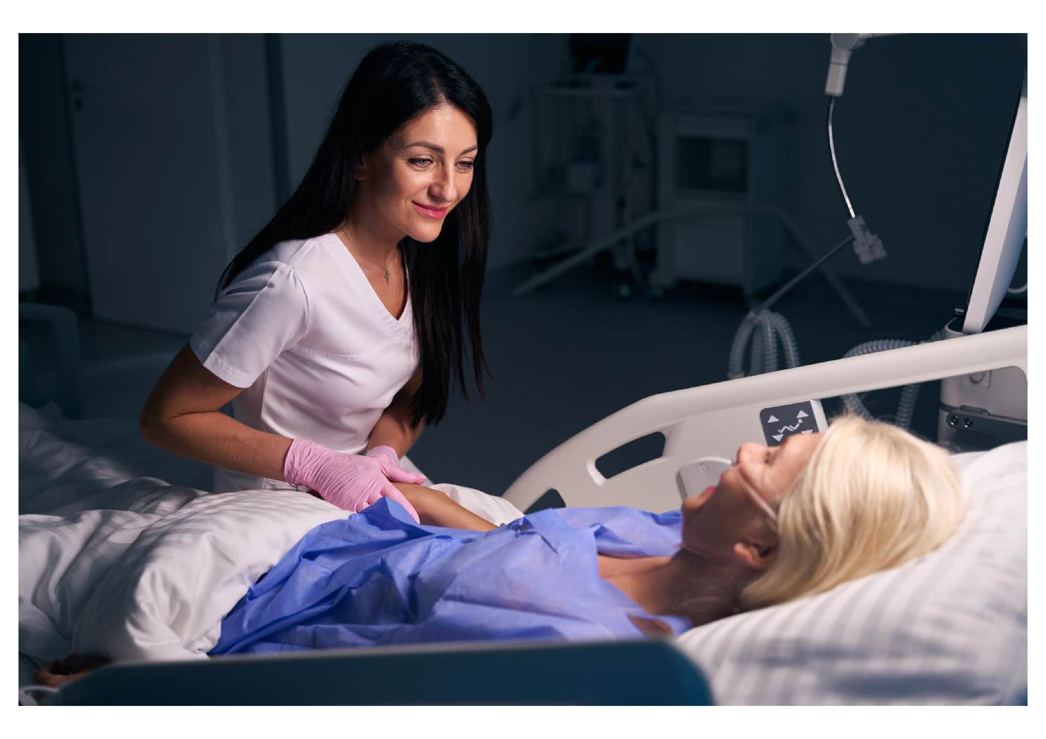 A nurse speaks gently to a woman lying in a hospital bed to help her fall asleep